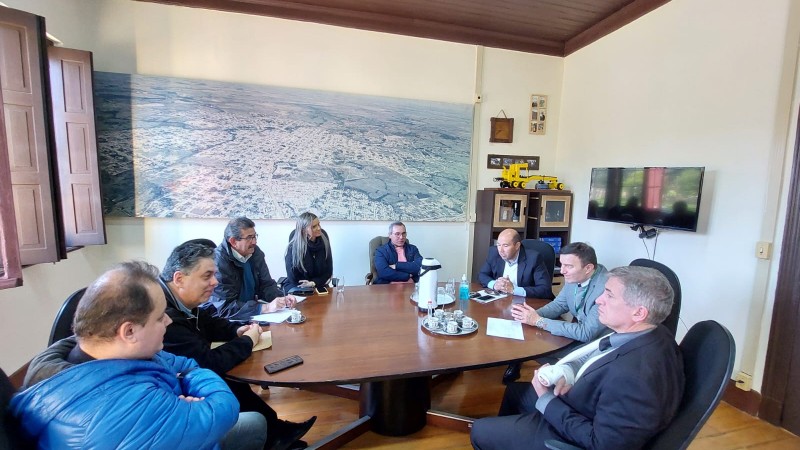 Foto da mesa de reuniões, redonda, com os representantes da defensoria e da prefeitura conversando