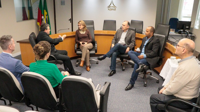 foto geral, de todos os 7 participantes da reunião, que estão sentados em um círculo, dentro do auditório da agergs