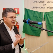 foto do defensor-geral discursando, com a galeria de fotos ao fundo, sendo tapada por um pano verde, que será descerrado