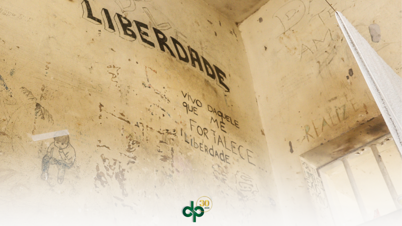 Imagem de uma cela de presídio em que se lê na parede "liberdade" e "vivo daquele que me fortalece"