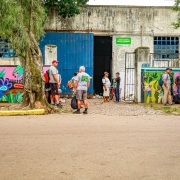 Pessoas conversam em frente à Unidade de Triagem. Grafites coloridos enfeitam o muro do local.