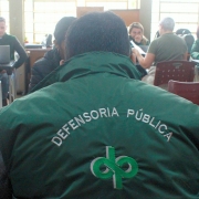 Servidor da DPE de costas com colete escrito "Defensoria Pública".