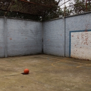 Foto de uma quadra poliesportiva com uma bola de basquete no centro