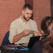 Na foto, há um defensor público prestando atendimento a uma mulher, que aparece de costas