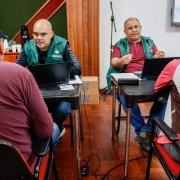 Na foto, há dois defensores de frente, atendendo duas pessoas, que aparecem de costas 