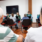 Na foto, há duas pessoas em primeiro plano, desfocadas, de costas, aguardando atendimento. Ao fundo, já pessoas sendo atendidas por defensores e servidores