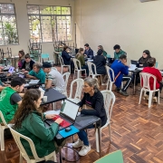 foto geral da sala de atendimentos, com cinco mesas de cada lado da sala e todos os servidores e defensores atendendo