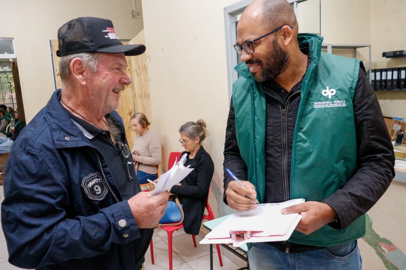 Foto geral de um defensor público conversando com um assistido