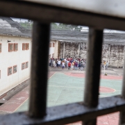 Fotografia do pátio da penitenciária. Ao fundo, vê-se homens reunidos conversando