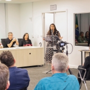 Paula Simões Dutra de Oliveira discursa em frente à plateia.