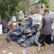 Homem em pé de frente a sacos de lixo