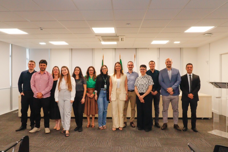 Treze pessoas de pé uma ao lado da outra posando pra foto.