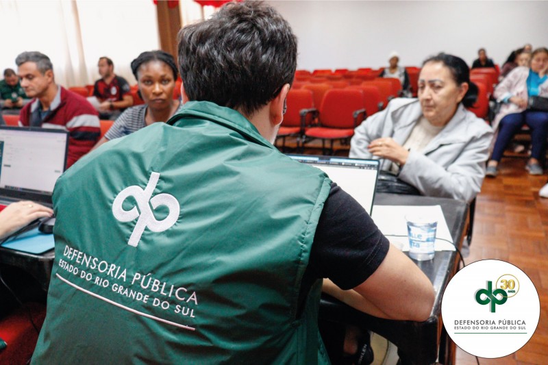 Foto geral de um defensor de costas prestando atendimento a um assistido