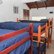 Quarto com 3 beliches, ventilador, janela, armário.