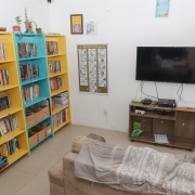 Sala de estar com sofá, TV, Videogame, armários e livros.