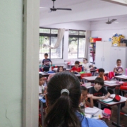 Paula observa sala de aula com alunos.