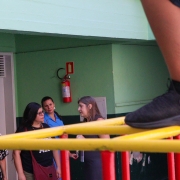 Ao fundo mulheres conversam sobre a condição da escola. Em primeiro plano aparecem os pés de criança em brinquedo.